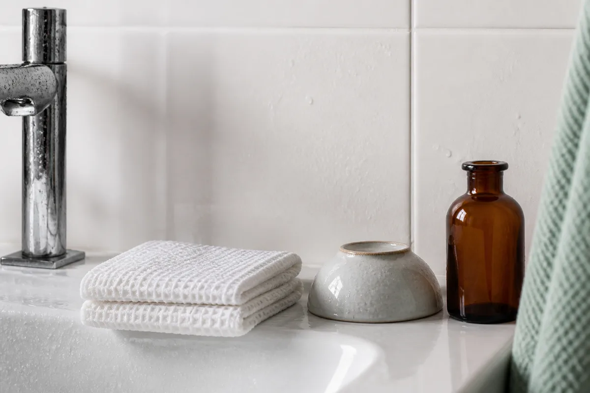 Gant de toilette propre et bol rincé posés au bord d&rsquo;un lavabo
